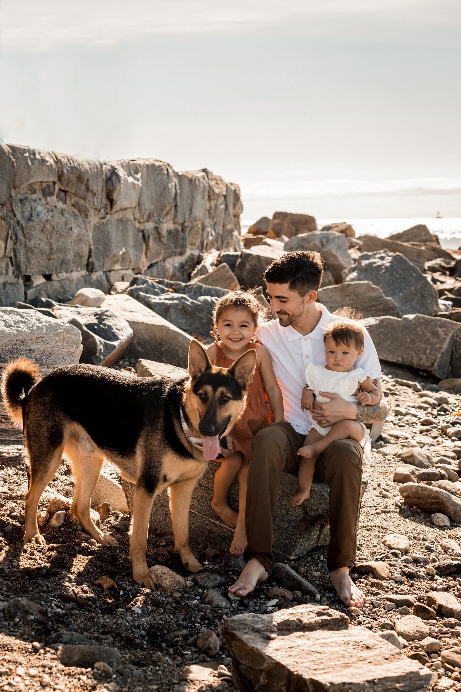 dad smiling with his kids and dog  on the beach