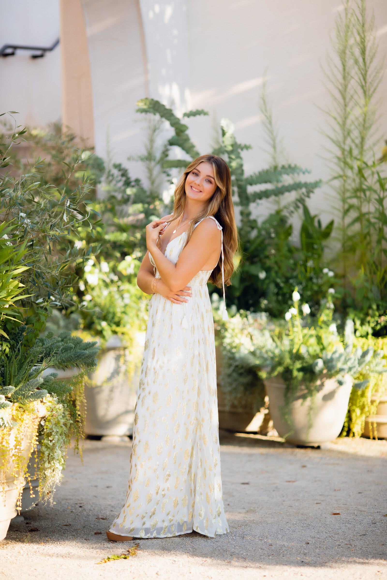 teenage girl  posing with a white dress surrounded by greenery