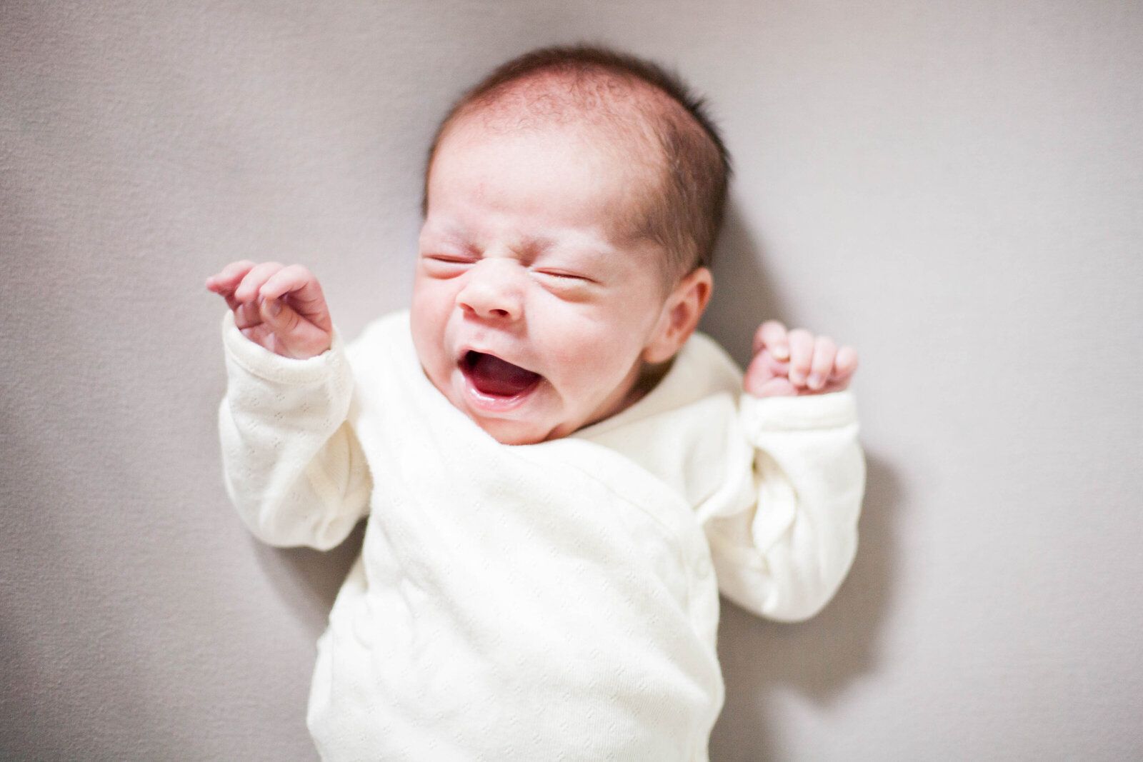 A baby wearing white yawning.
