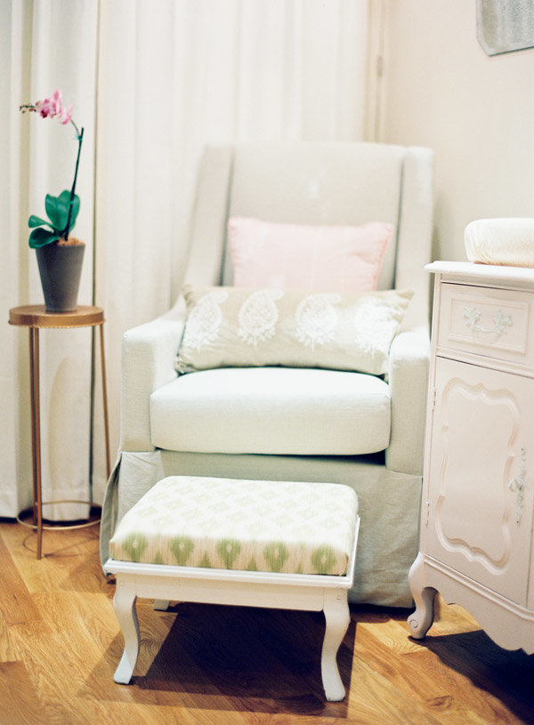 A light green rocking chair and foot stool in a nursery.