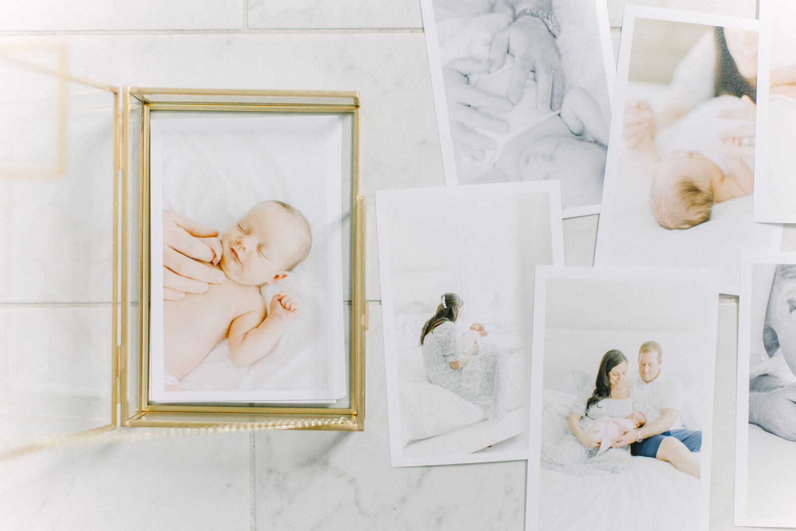 A flatlay photo of a loose pile of 4x6 printed images next to a glass box with brass accents