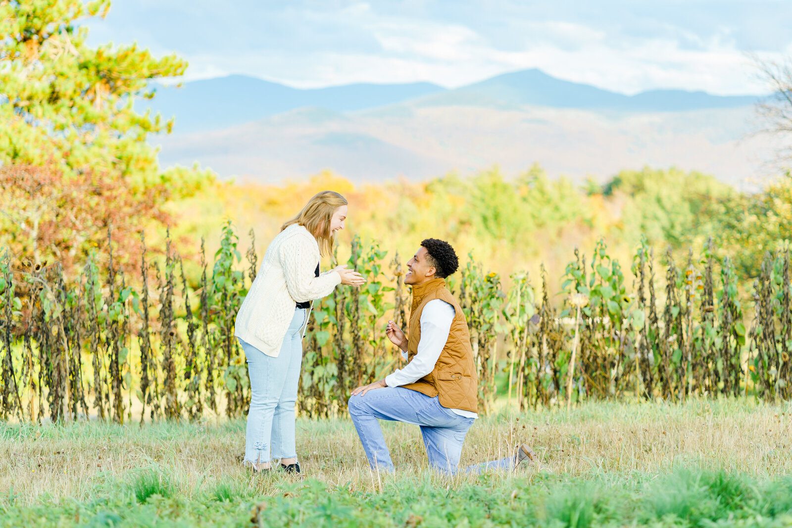 Man down on one knee proposing with New Hampshire mountains in background