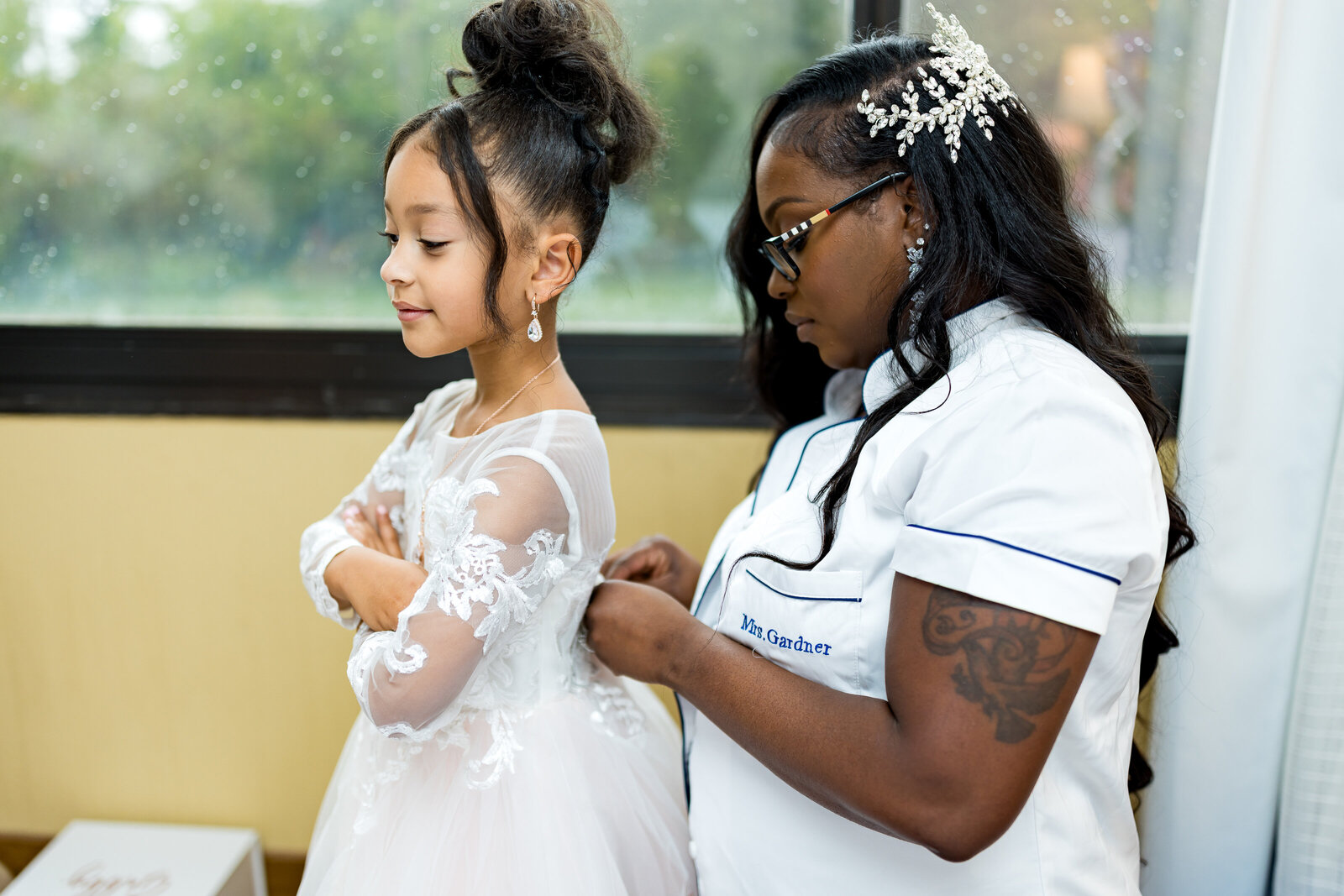 A black bride is getting her daughter ready in a hotel room.