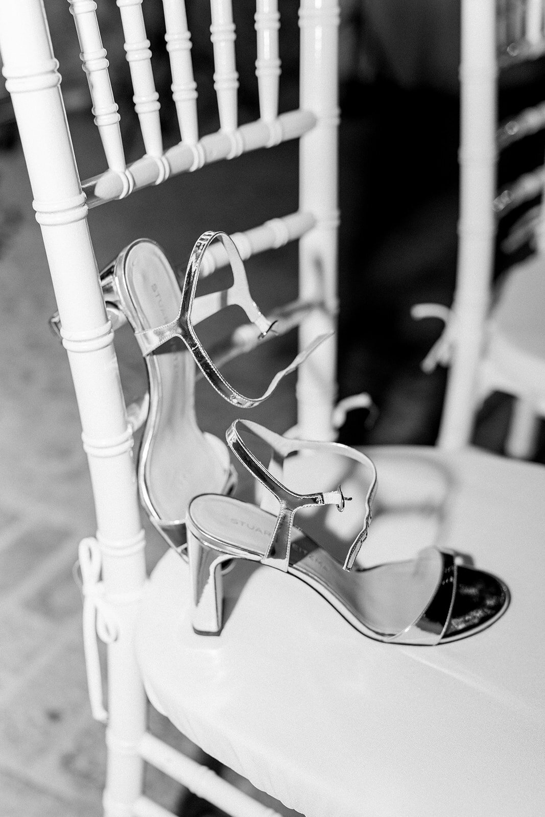 Artistic black and white film shot of a white ceremony chair with ribbon, captured at a Hummingbird Nest Ranch wedding.