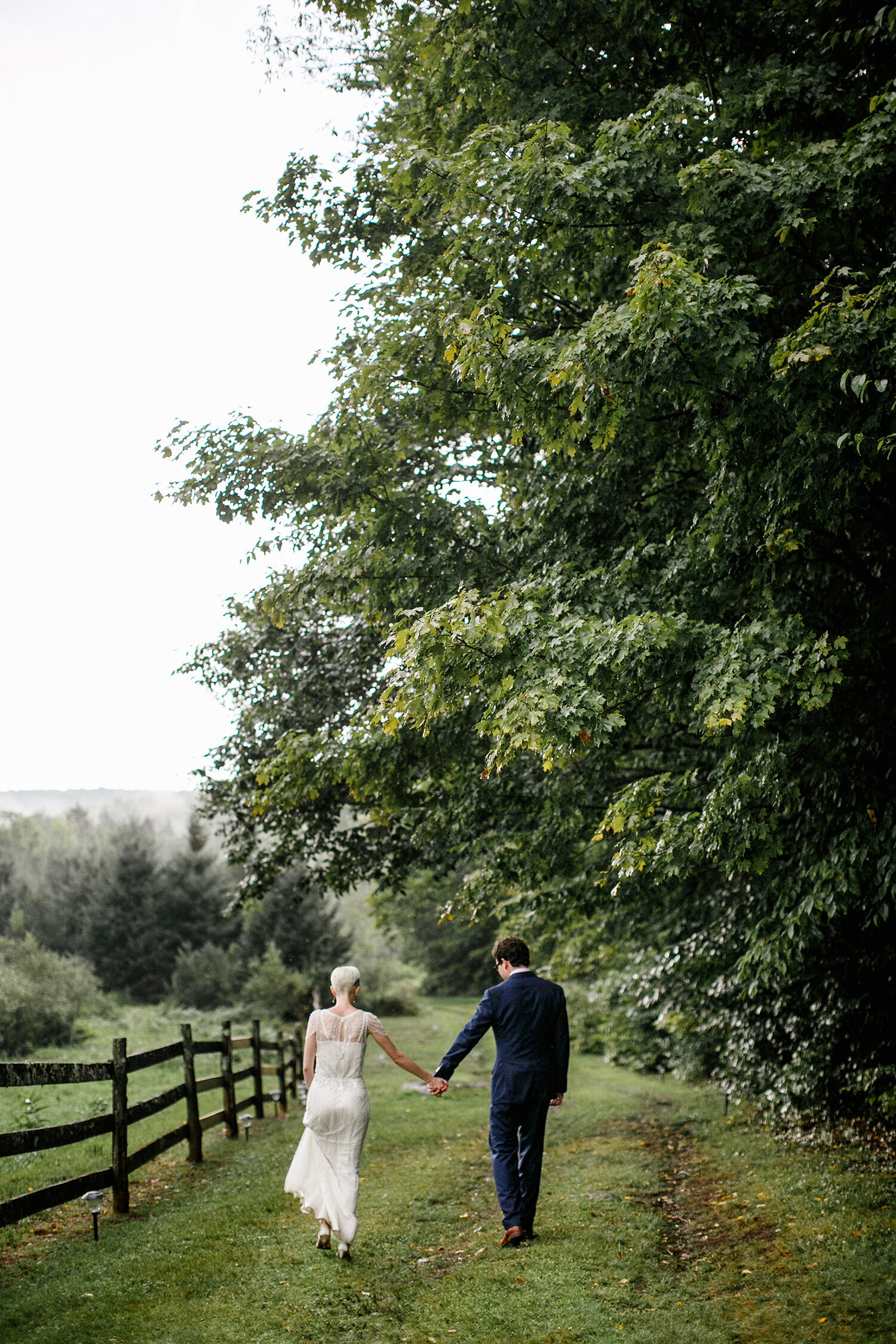 bride and groom walking down tree covered farm path
