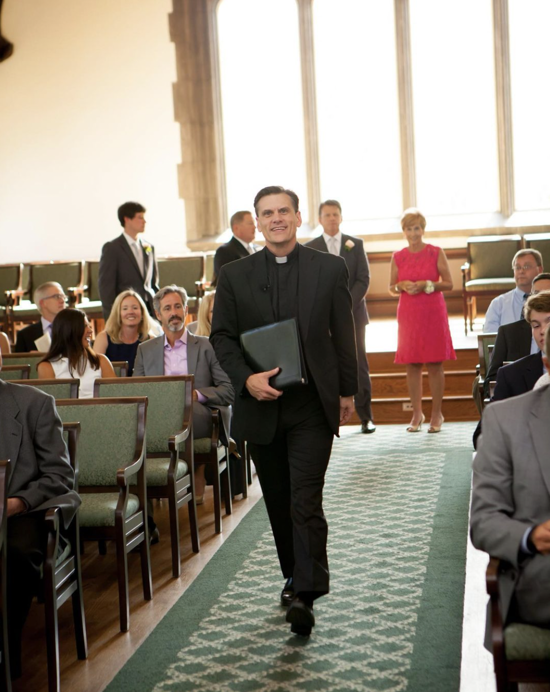 Wedding officiant walks down the aisle to lead wedding ceremony in church