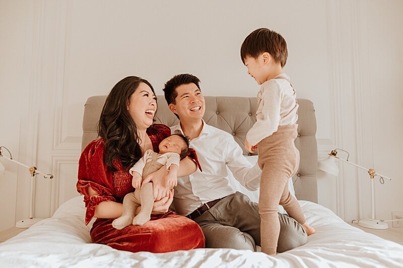 Photo of family playing on bed with newborn baby by Vancouver newborn photographer