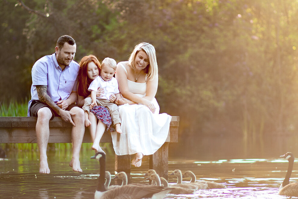 Family sit together on a dock during family photoshoot in Plymouth