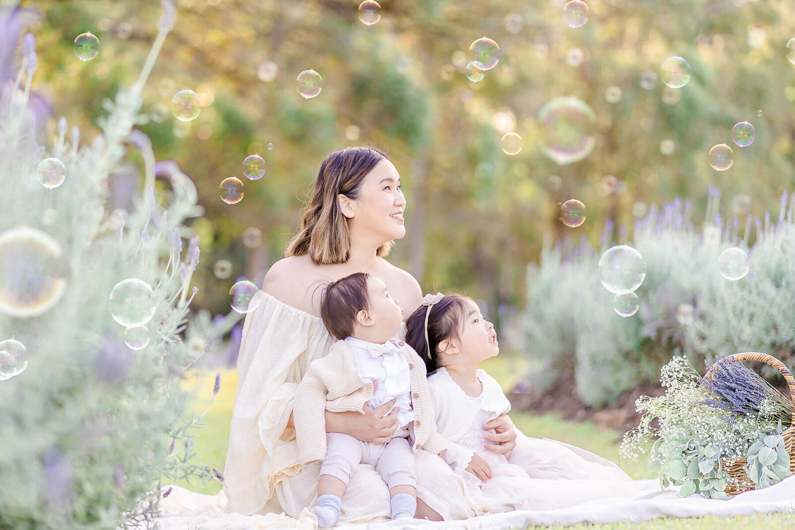 mum holding two young kids in brisbane sirromet lavender field blowing bubbles