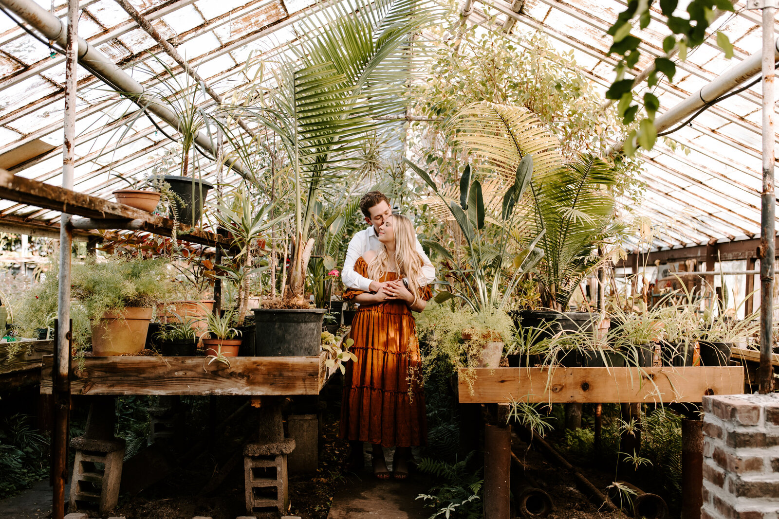 Couple embracing in green house engagement photos