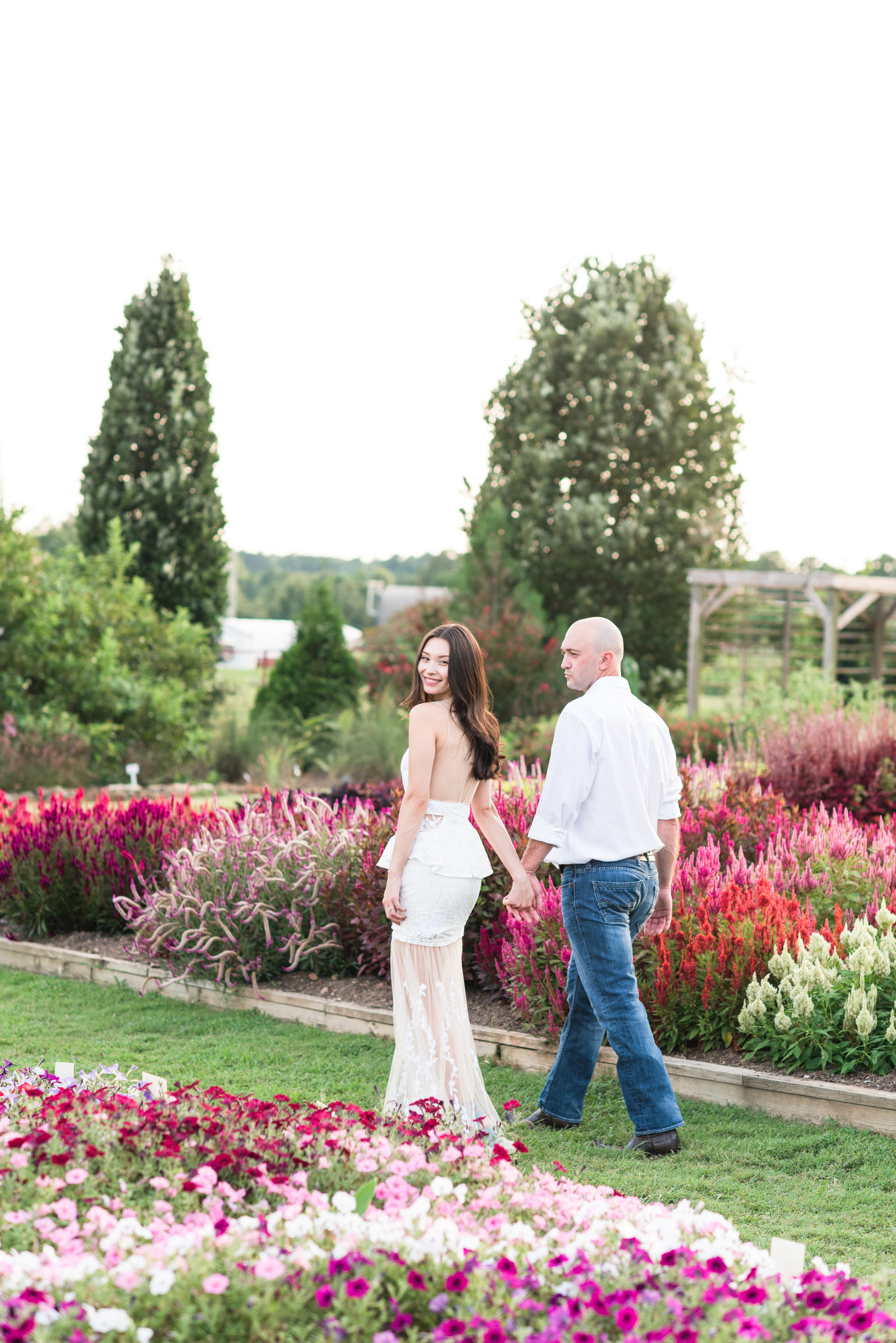 bride and groom walking in a flower garden at JC Raulston Arboretum with the bride looking back at the camera