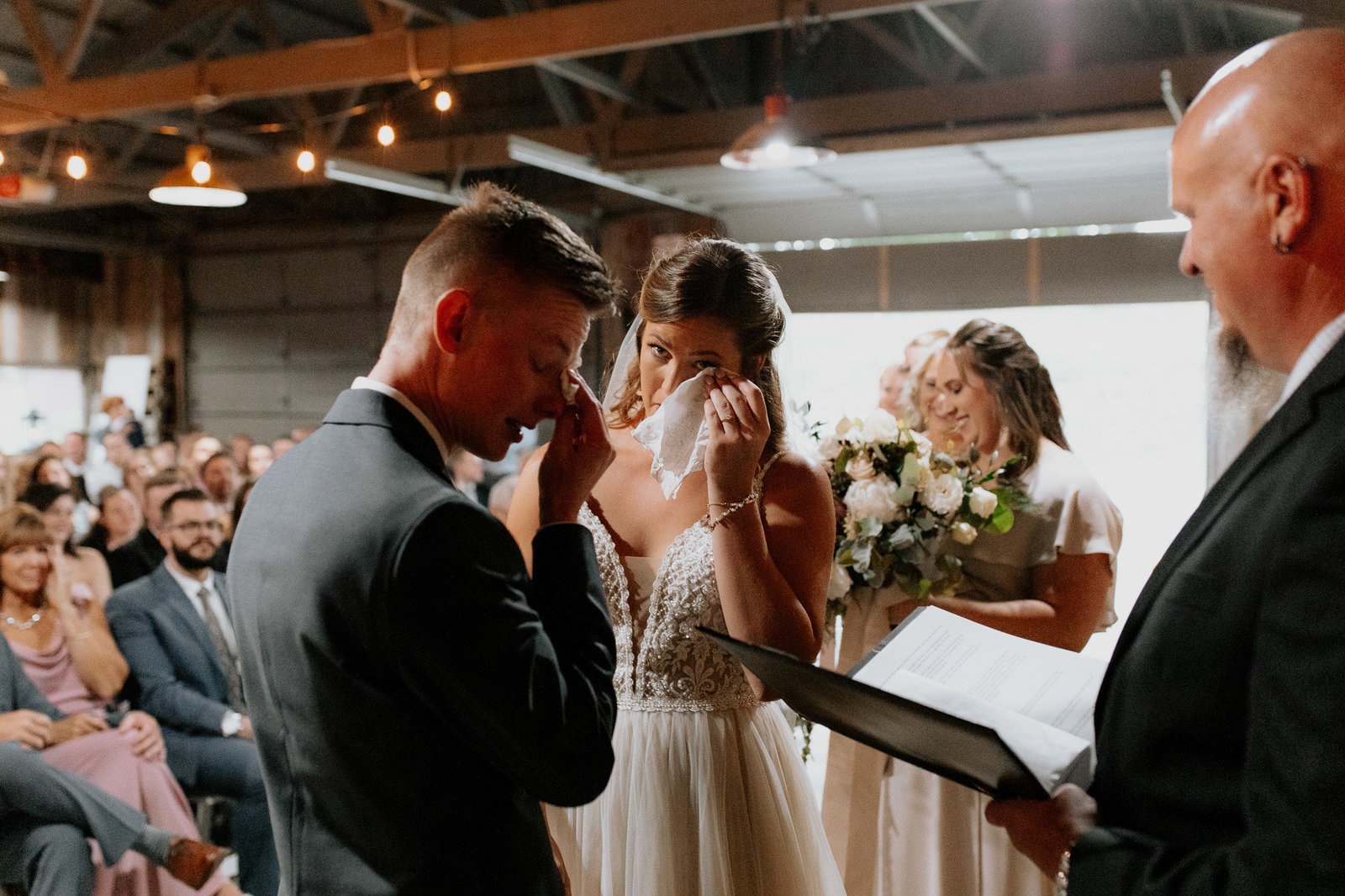 Groom and bride crying as they say their vows in a  Denver barn.