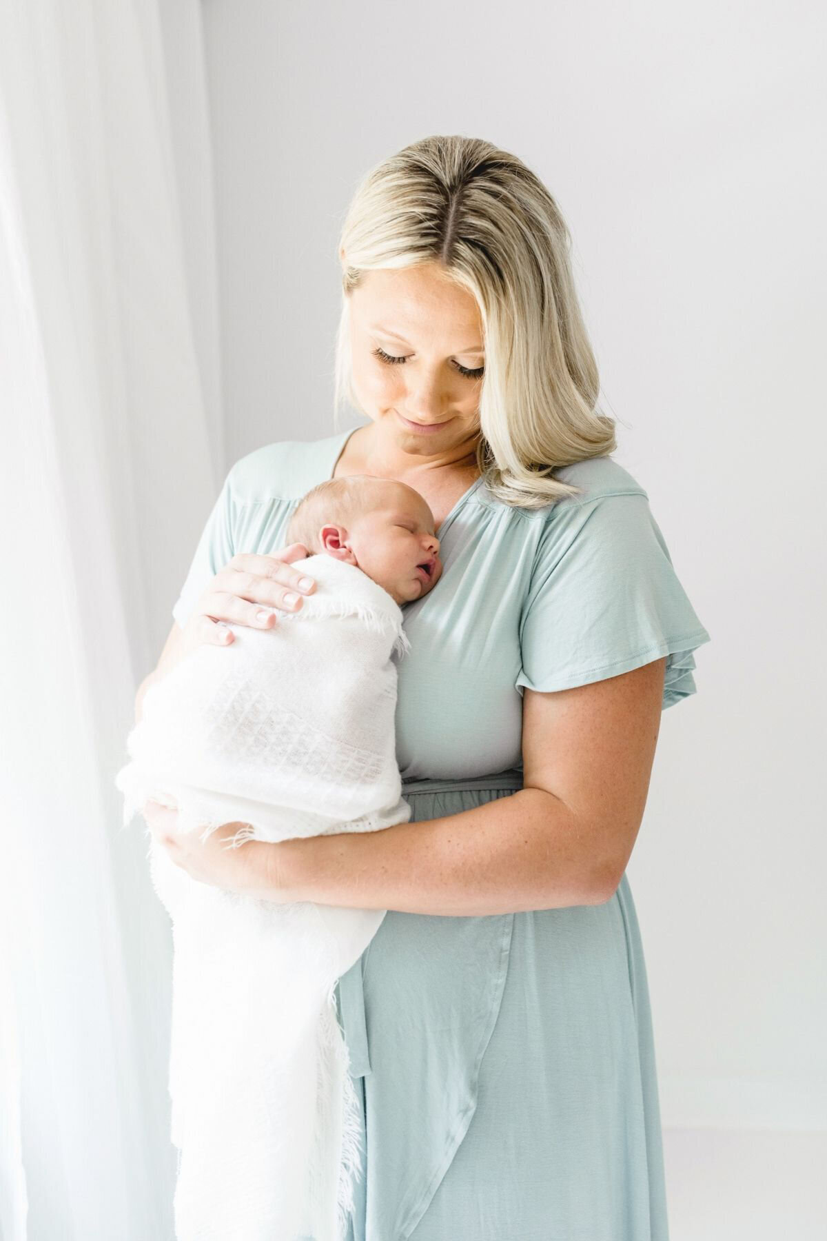 Mom holding newborn by Charlotte Newborn Photographer Anna Wisjo