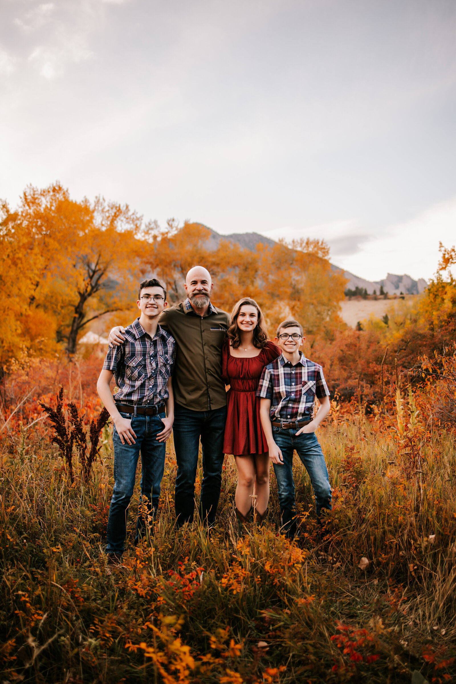 dad stands with teenage children in the middle of an aspen field in boulder colorado