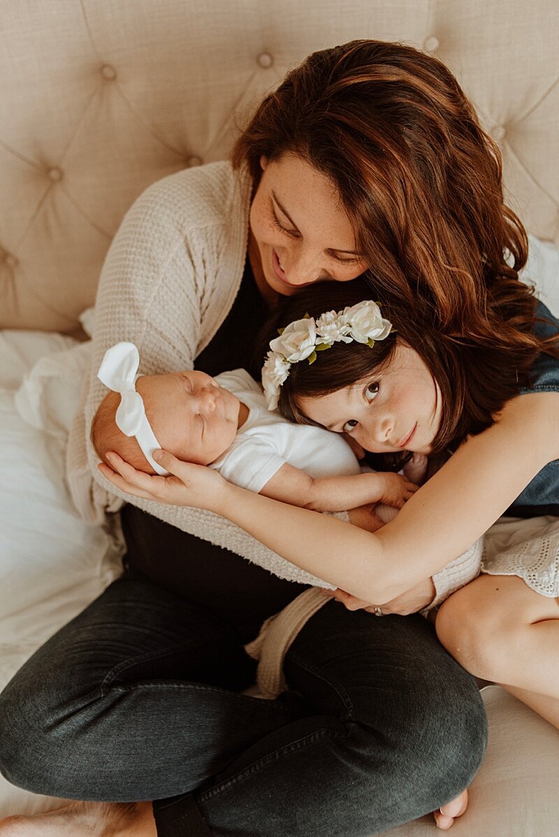 Mom and sister snuggling baby during newborn photography sessions