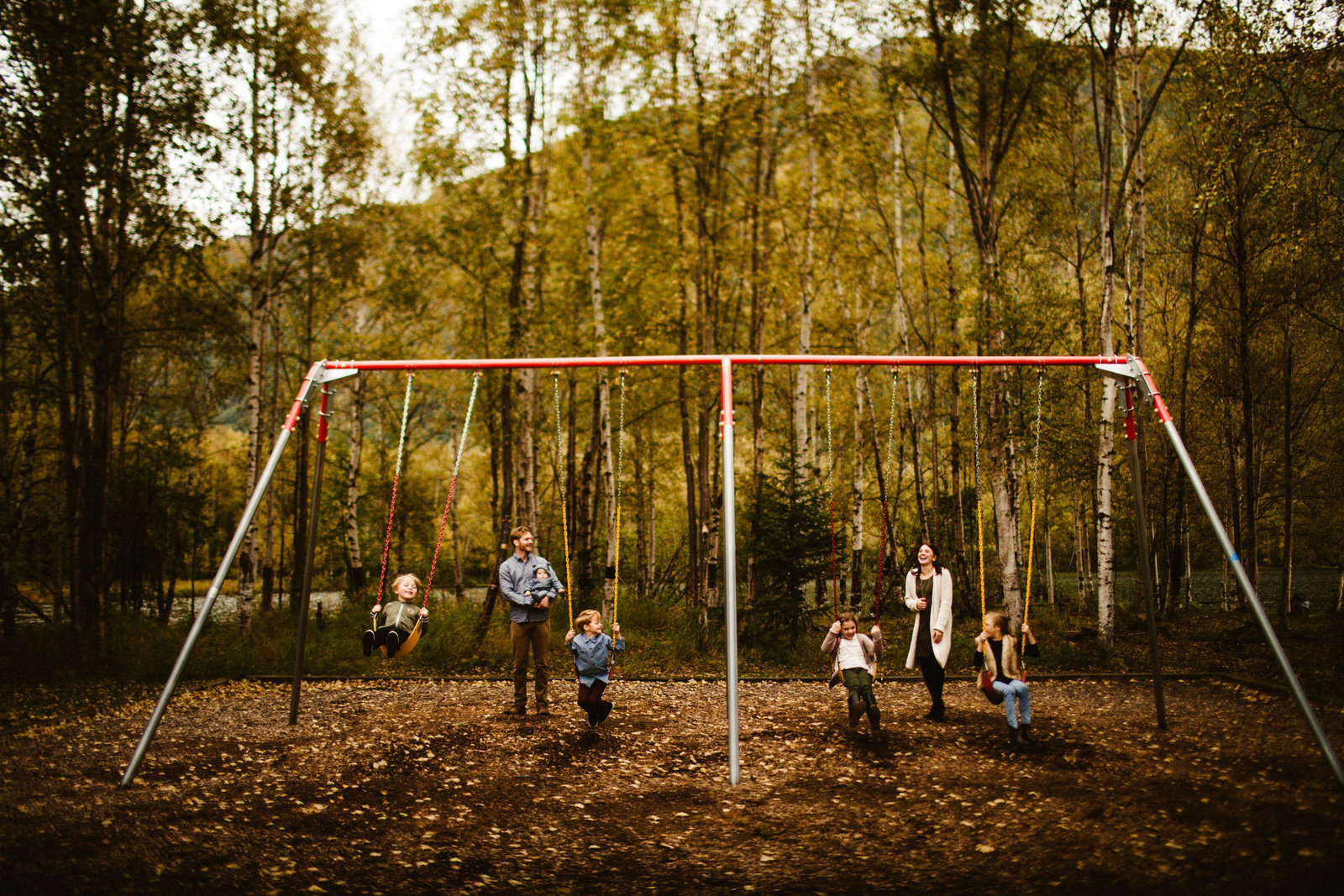 family with five children on a swing set in the fall