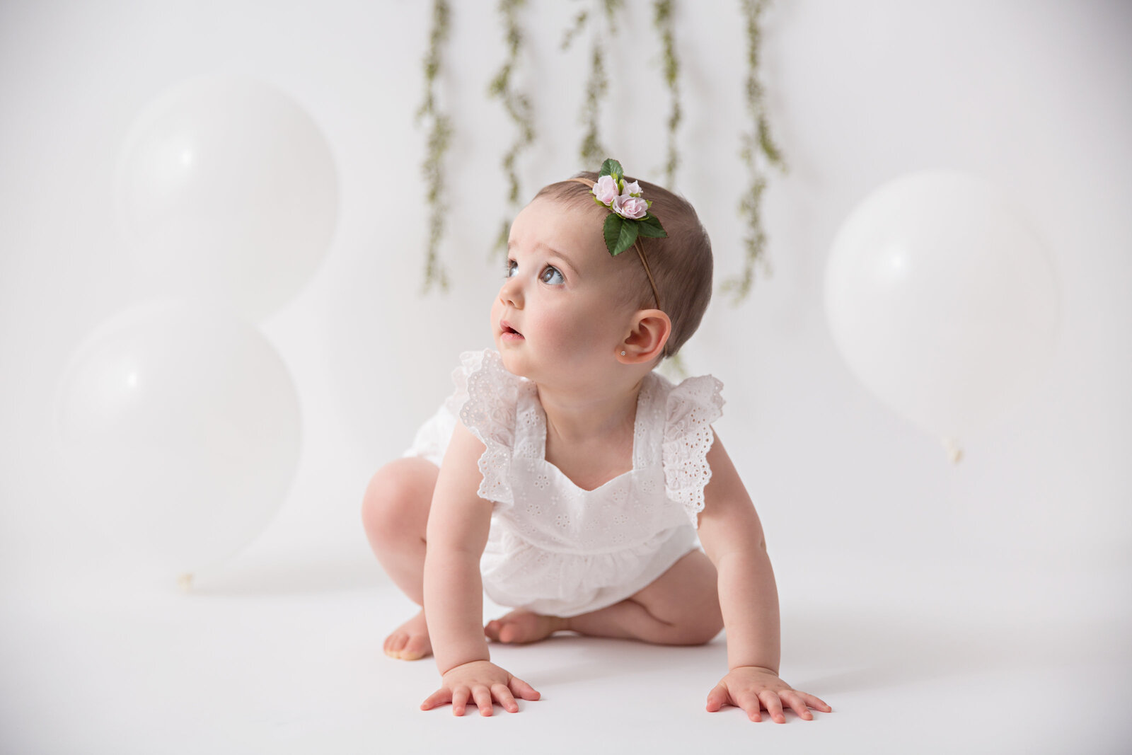 baby girl white backdrop white balloons greenery