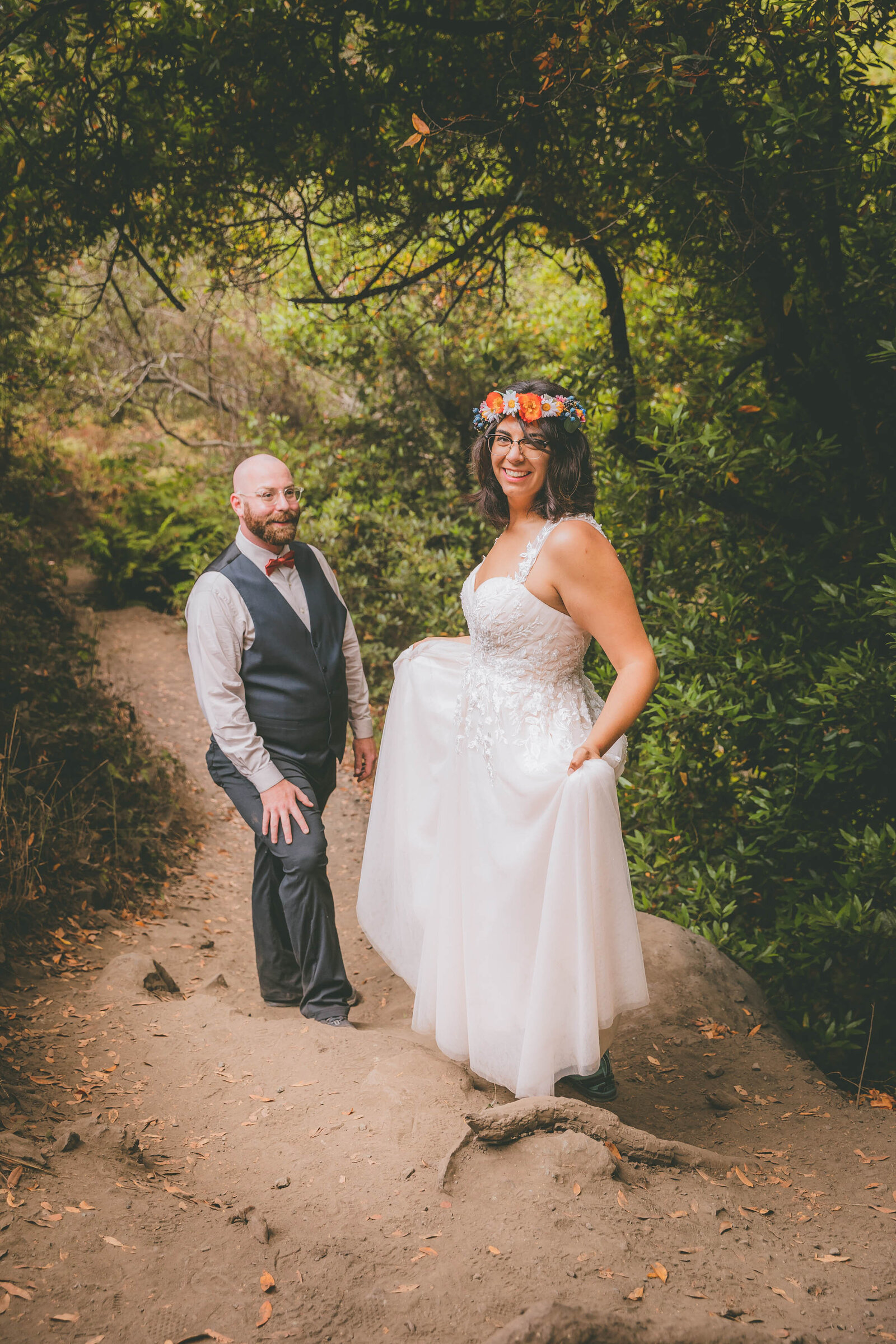 A groom and bride wearing a flower crown hike down a path for their Cambria Big Sur elopement.