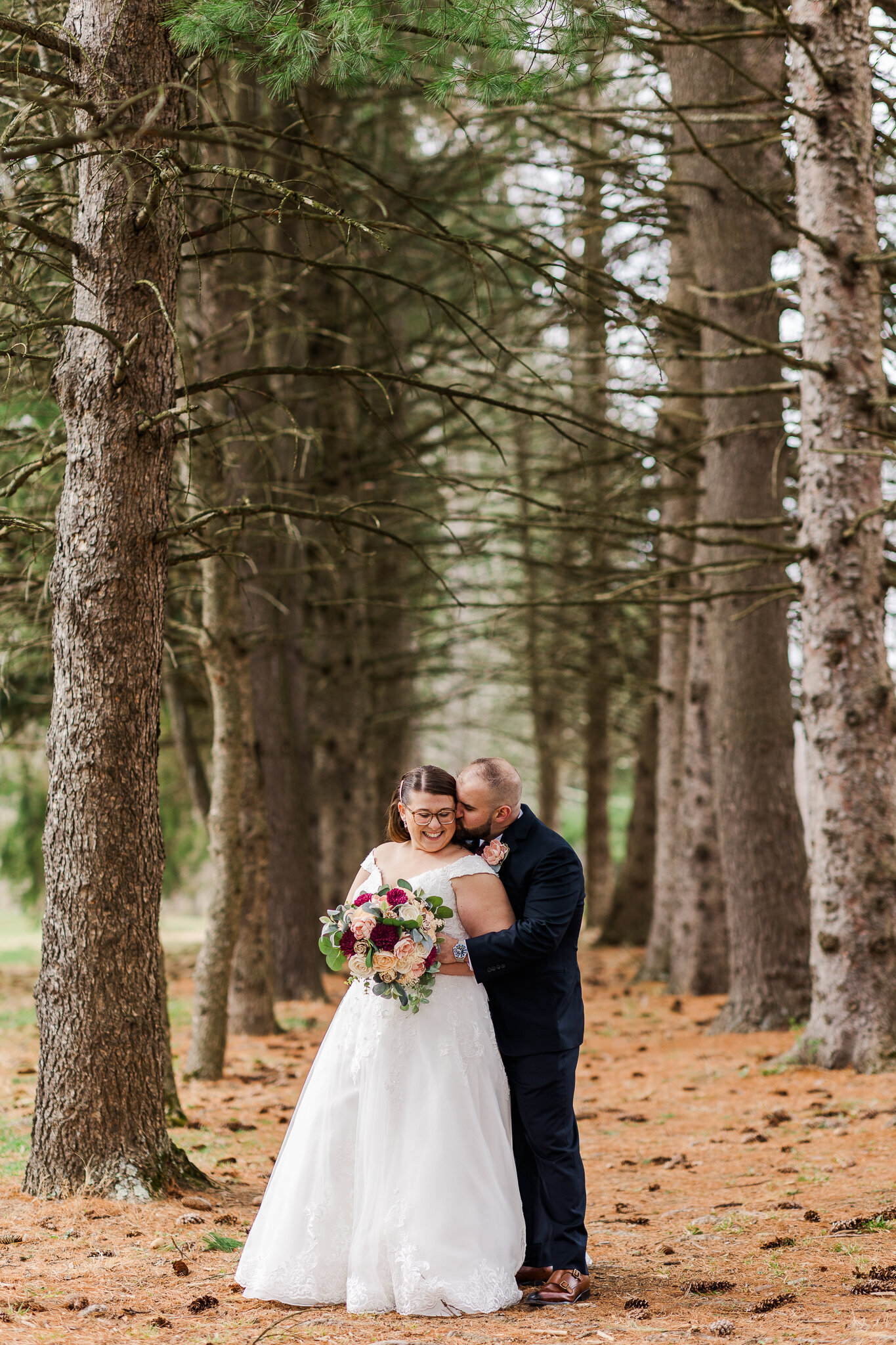 groom snuggles in on bride in forest