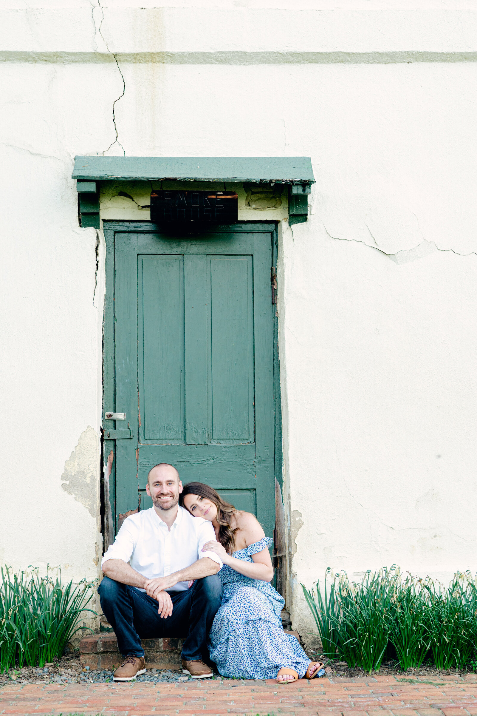 COuple sits in front of green door surrounded by grass
