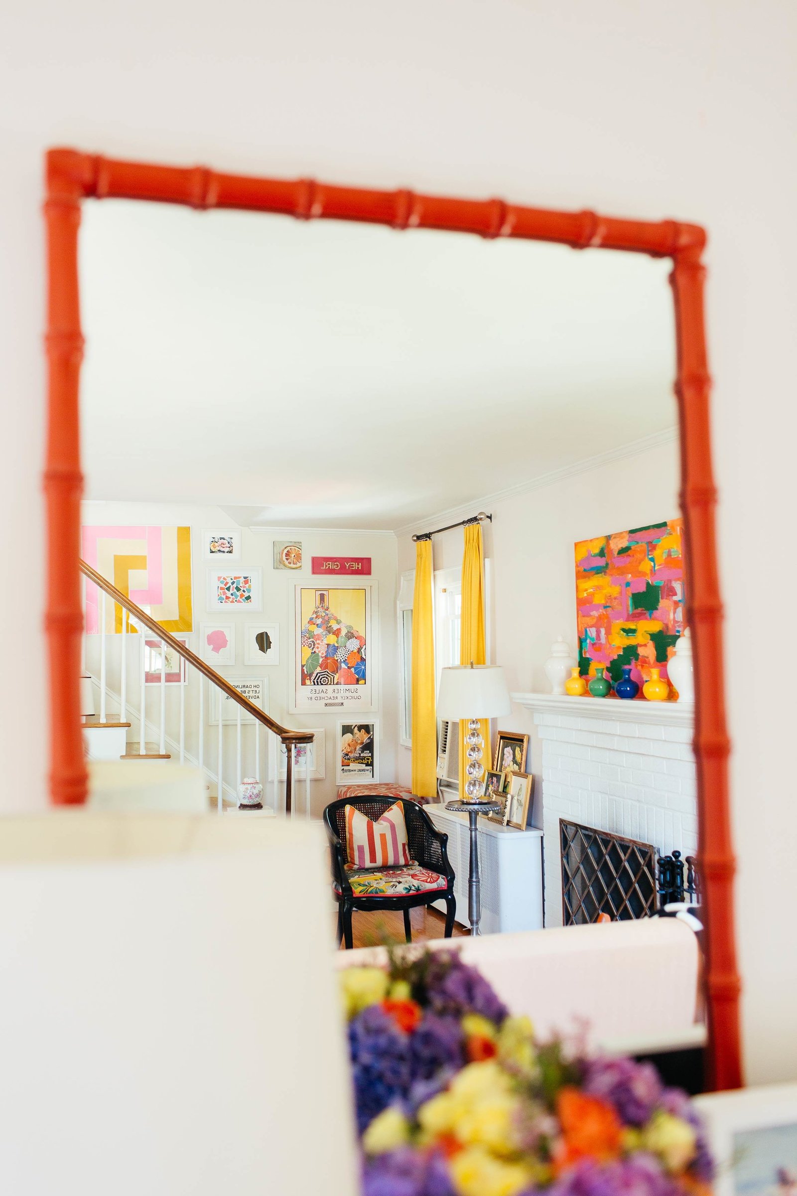 A dark orange framed mirror reflecting a colorful living room.
