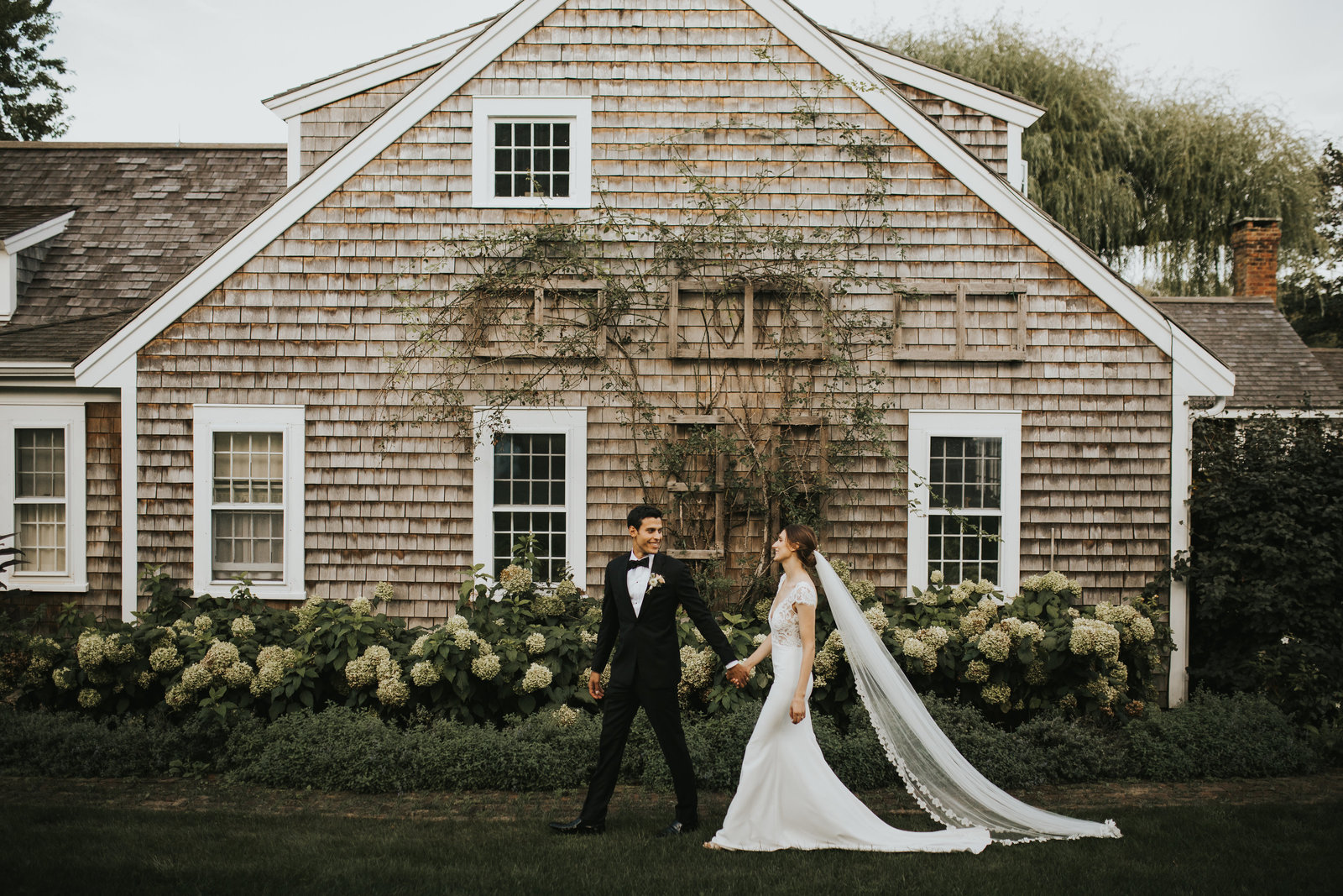 bride and groom walking past Cape Cod rustic venue cottage