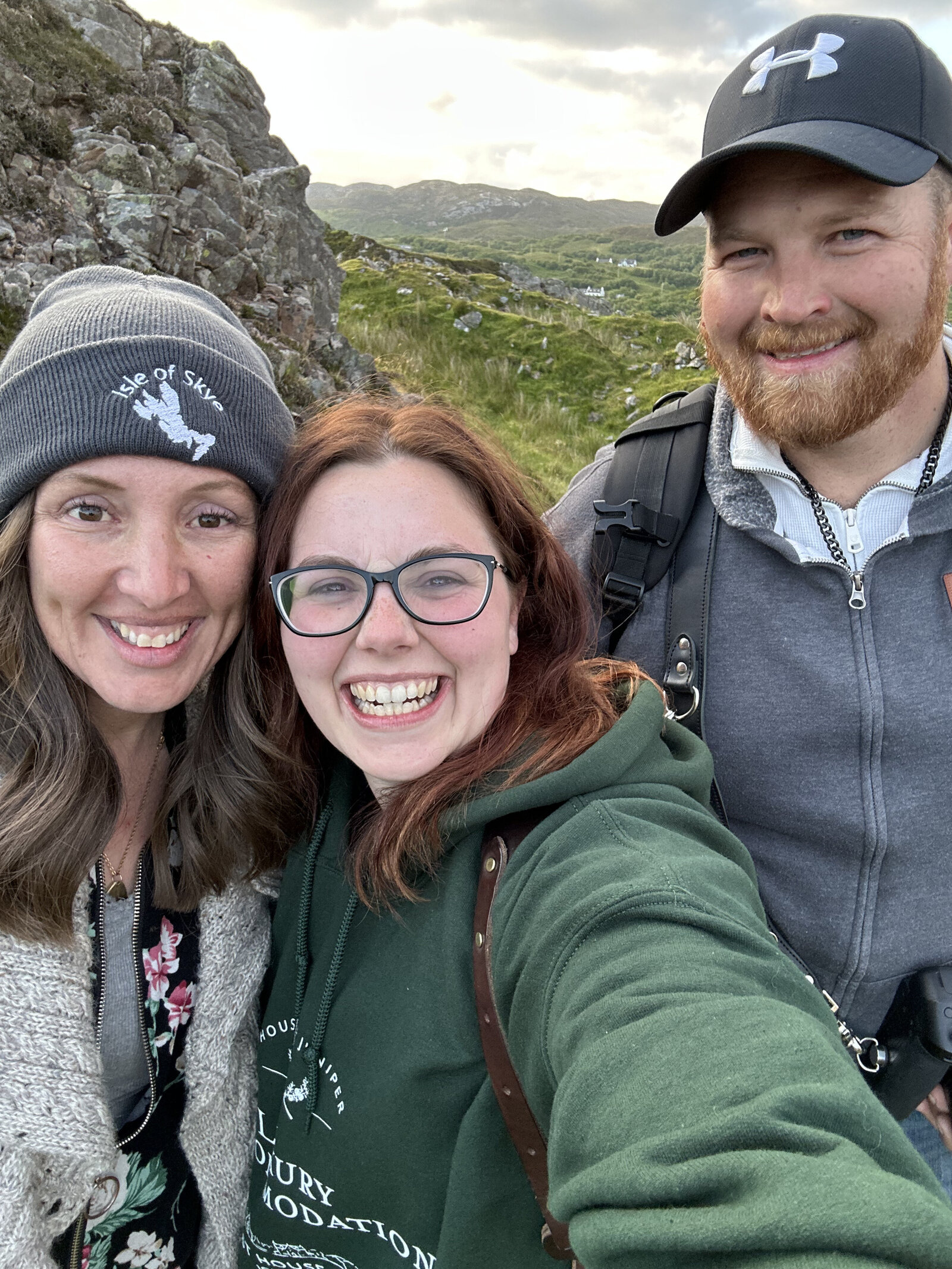 Three people smiling outdoors with rocky hills and a green landscape, capturing the spirit of an Italy photography retreat in the countryside for inspired storytelling.