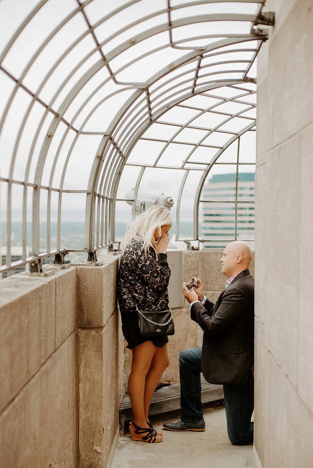 Man proposing to his girlfriend on one knee at the top of the Foshay building in Minneapolis