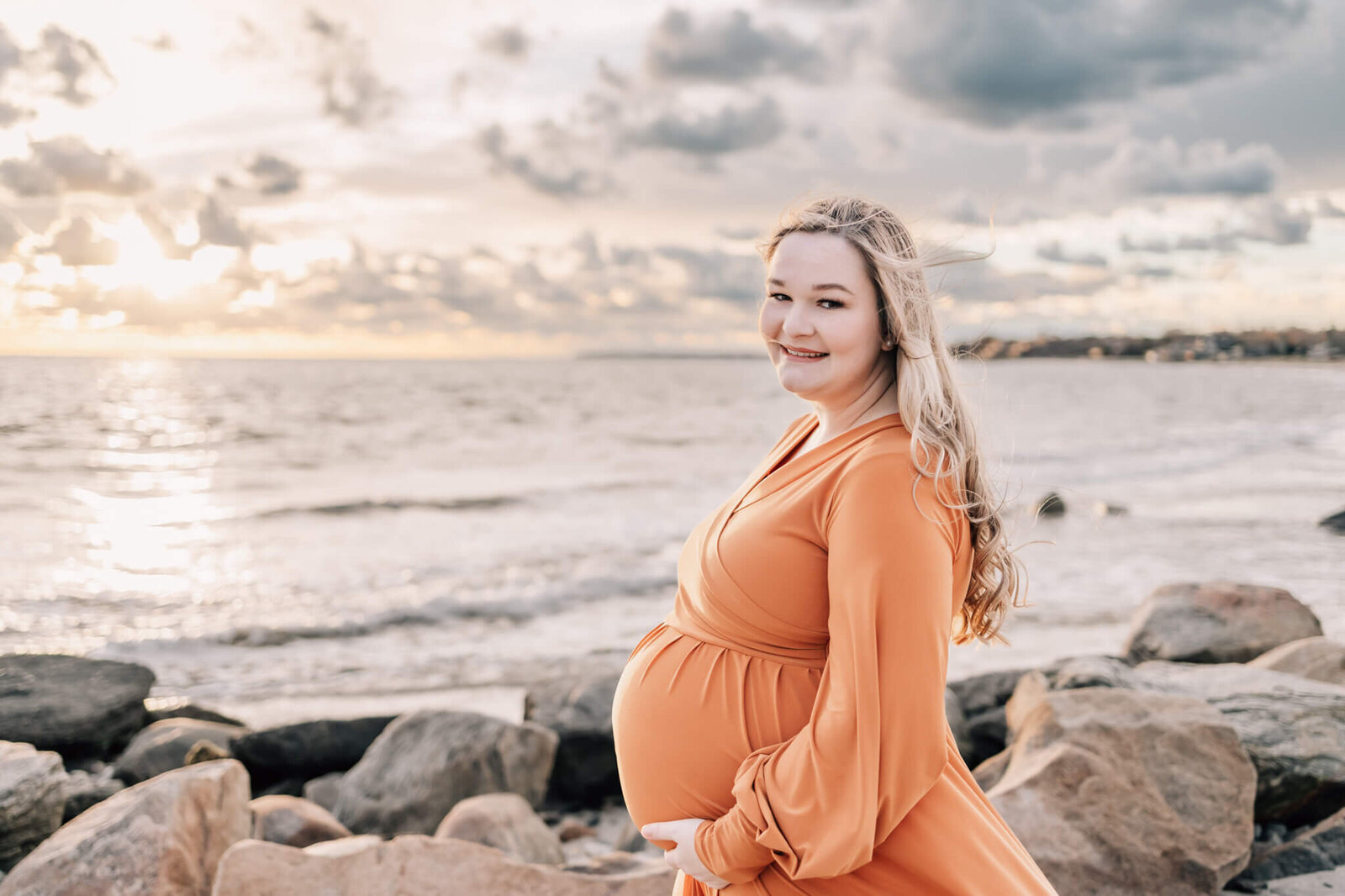 maternity photo session in orange dress in front of beach