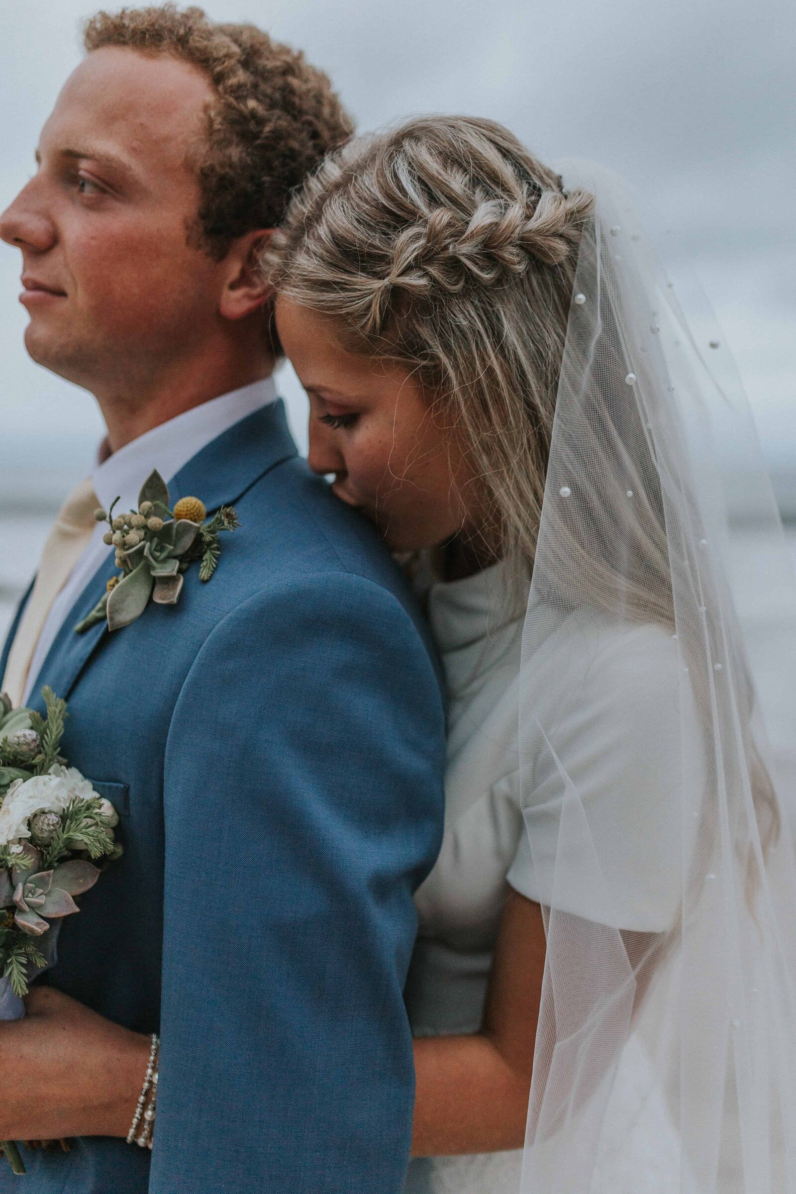 Sacramento Wedding Photographer captures bride kissing groom's shoulder after beach elopement