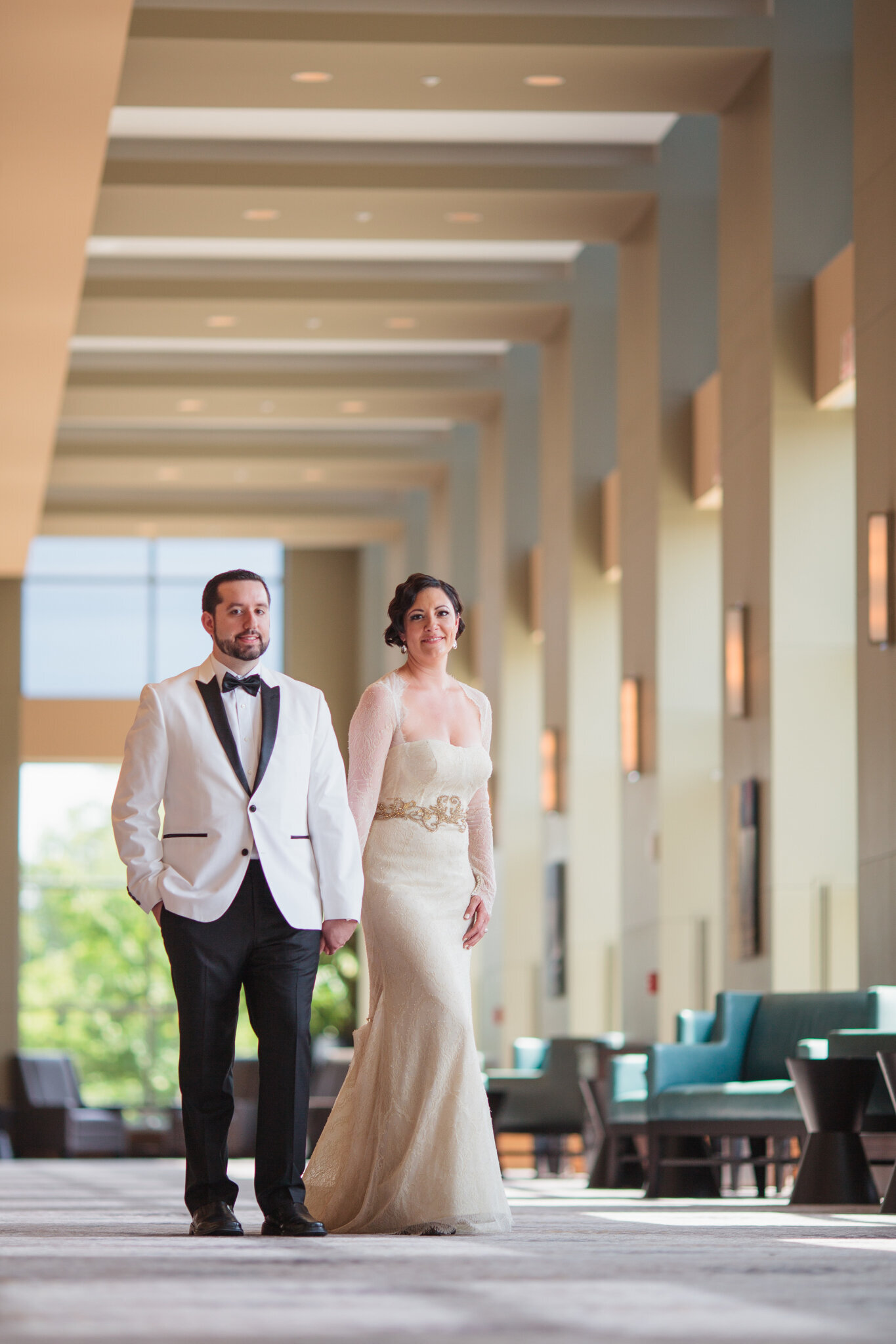 Bride and groom hold hands and walk through venue lobby