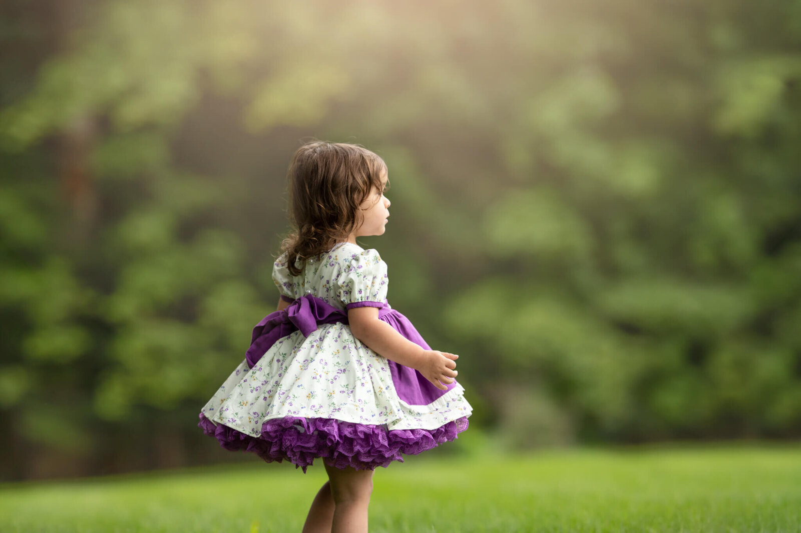 Toddler girl in vintage dress looking off in distance to the right
