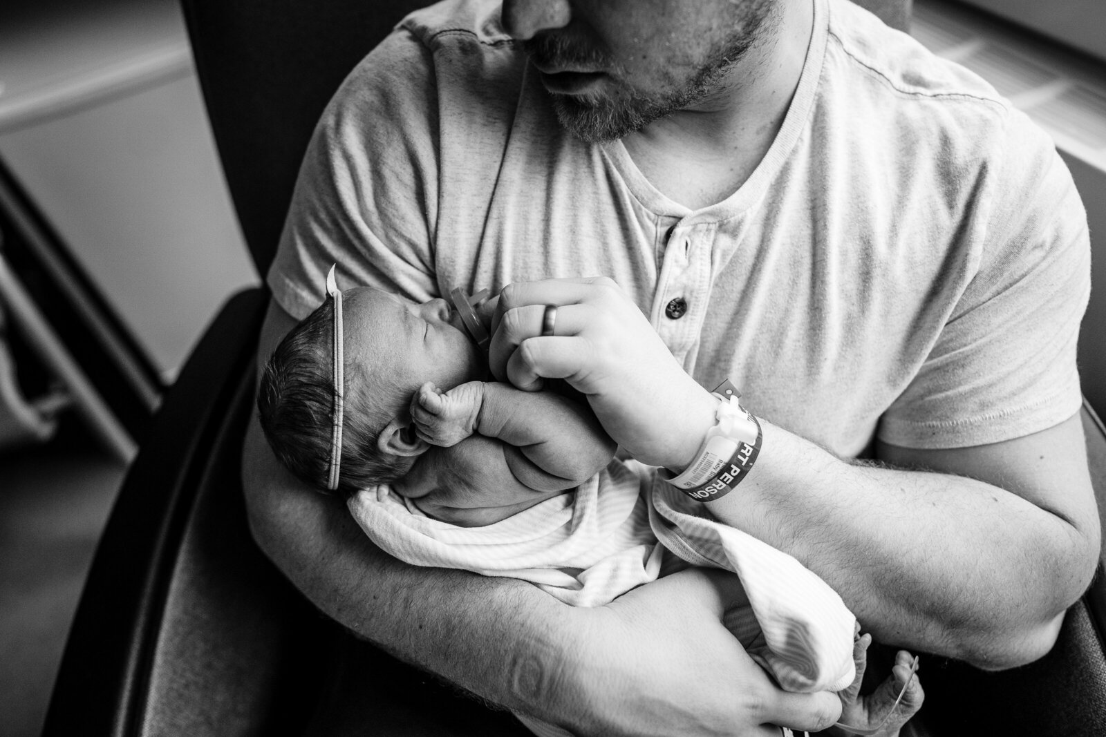 dad stares down at newborn wrapped in hospital blanket