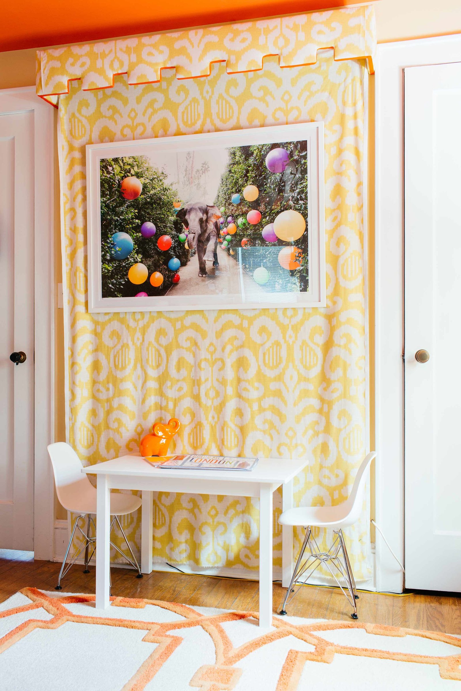 Yellow damask drapes hang behind a white table and two chairs.