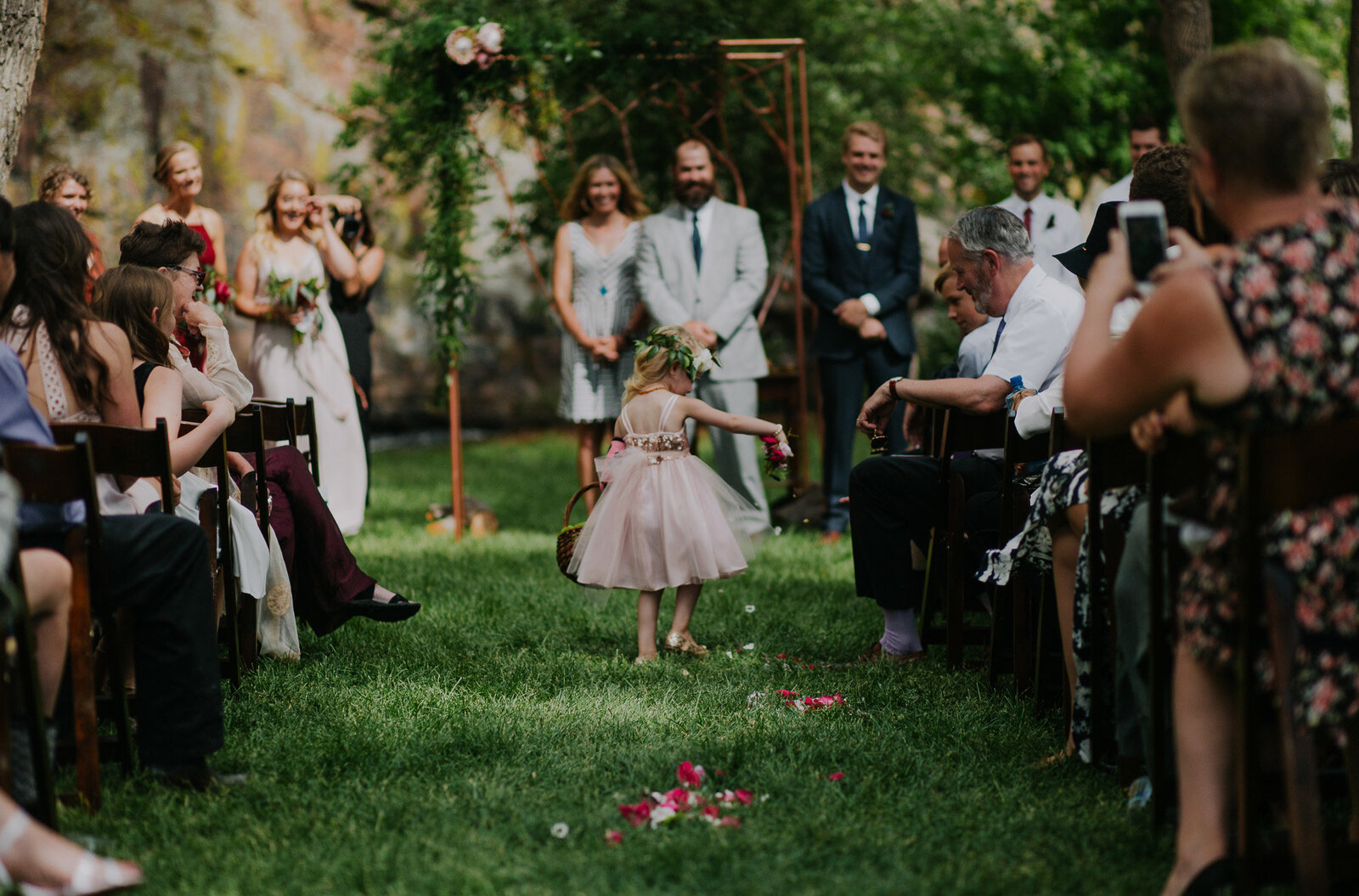adorable photo of flower girl dropping petals down the grass aisle at planet bluegrass wedding