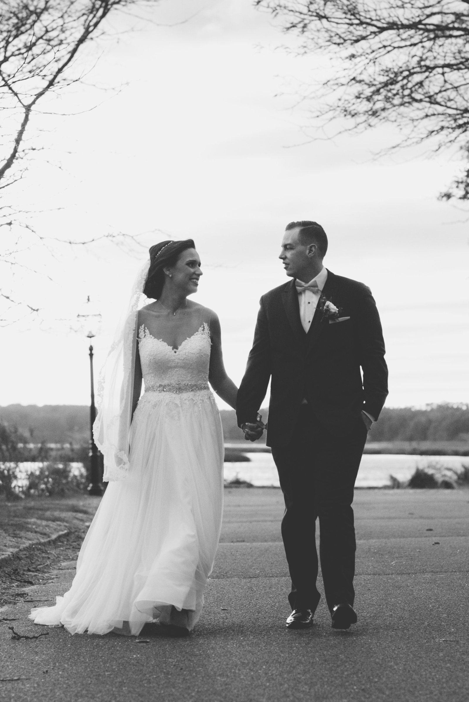 black and white photo of bride and groom holding hands and walking from wedding at Three Village Inn
