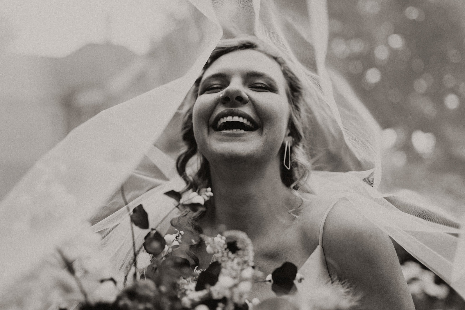 bride smiling happily in black and white photo near st vrain river in Longmont colorado