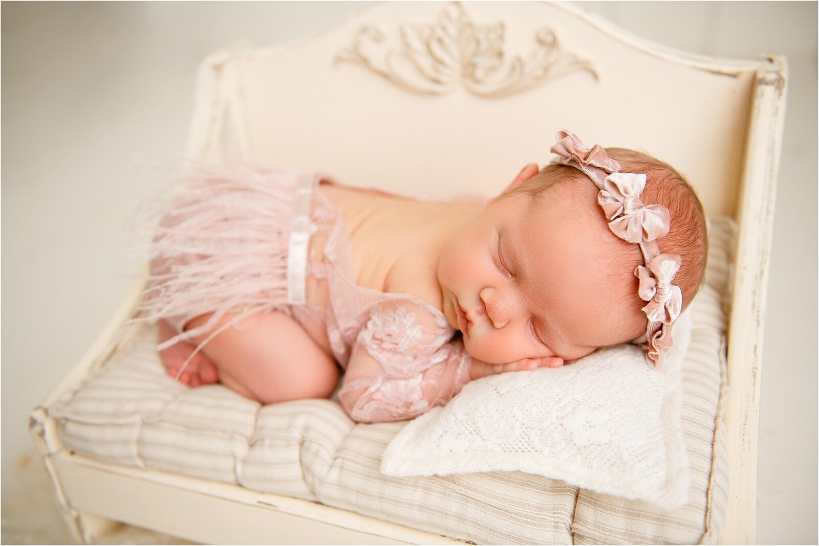 newborn girl in pink lace onesie