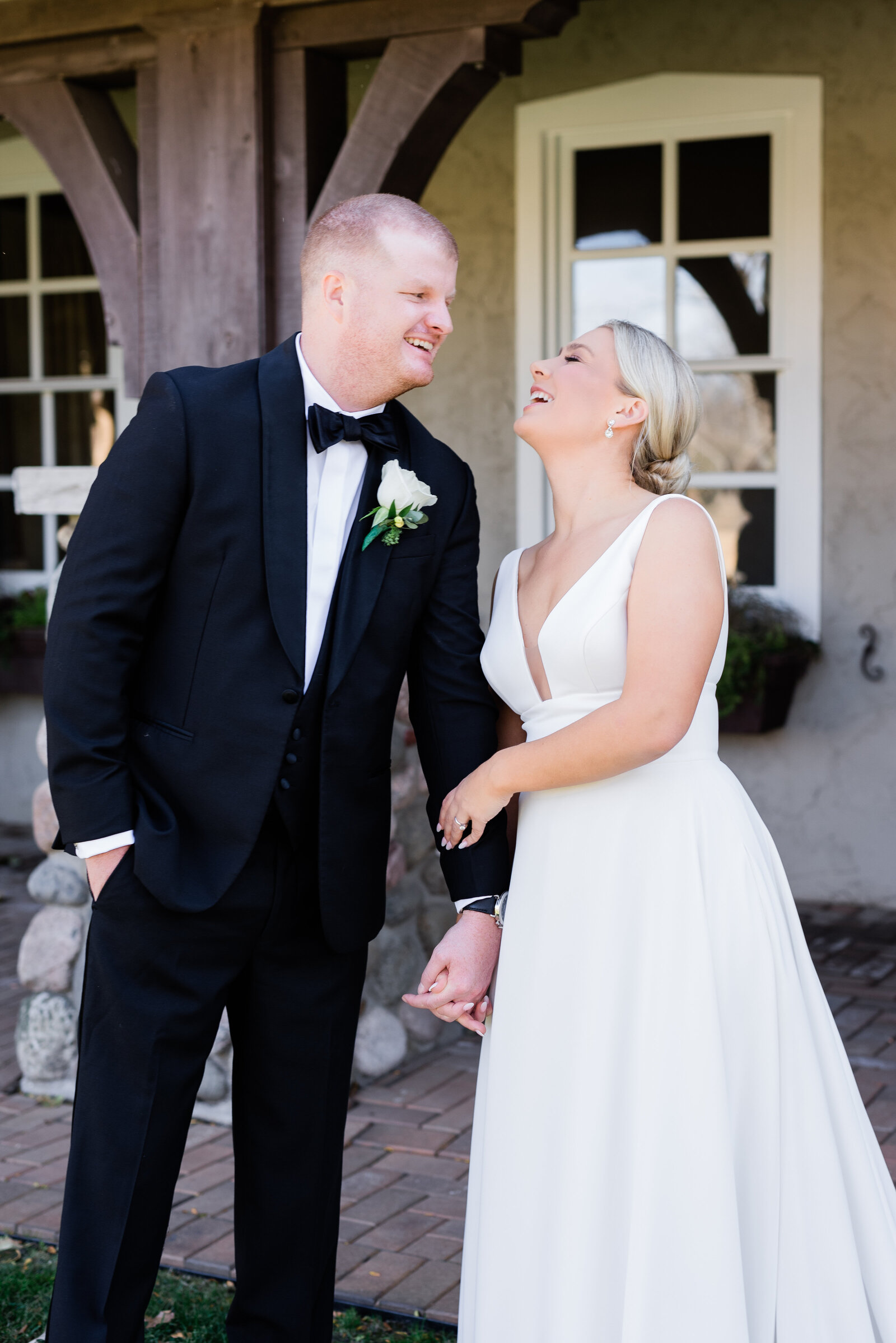 Wedding couple laughing at each other holding hands.
