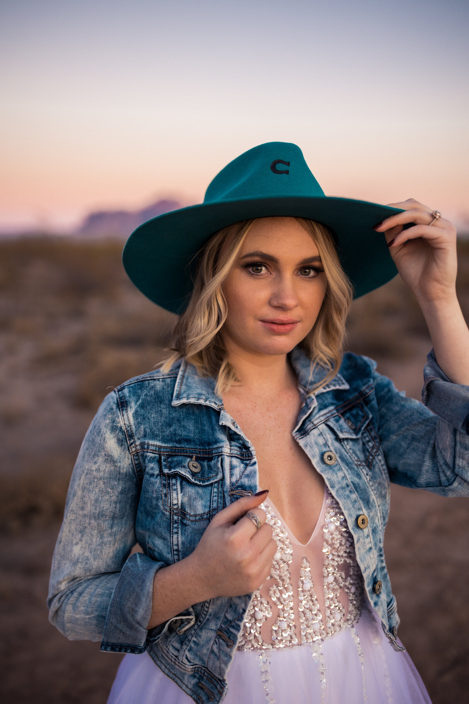 bride with beaded dress, jean jacket, and turquoise charlie one hat