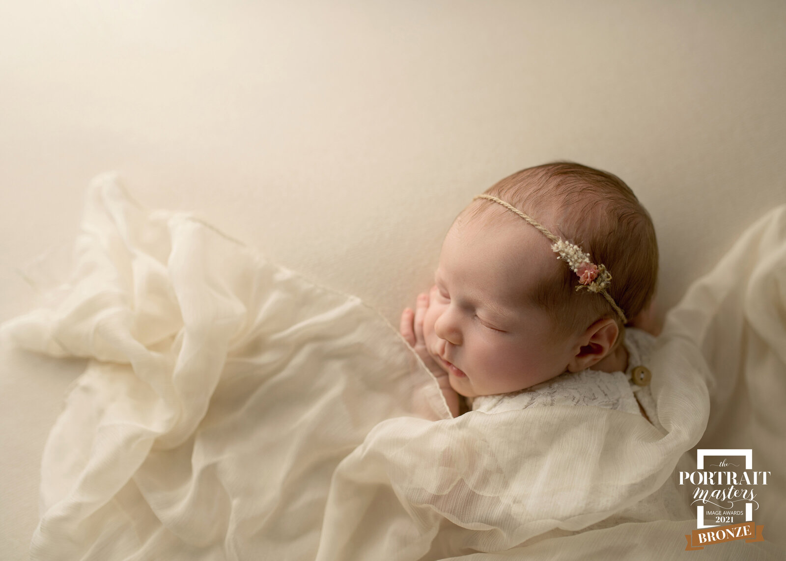 Portrait Masters Bronze newborn portrait with cream and floral accents