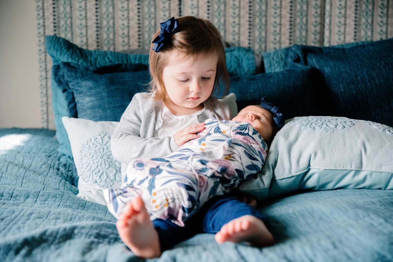 Girl holding newborn sister pose