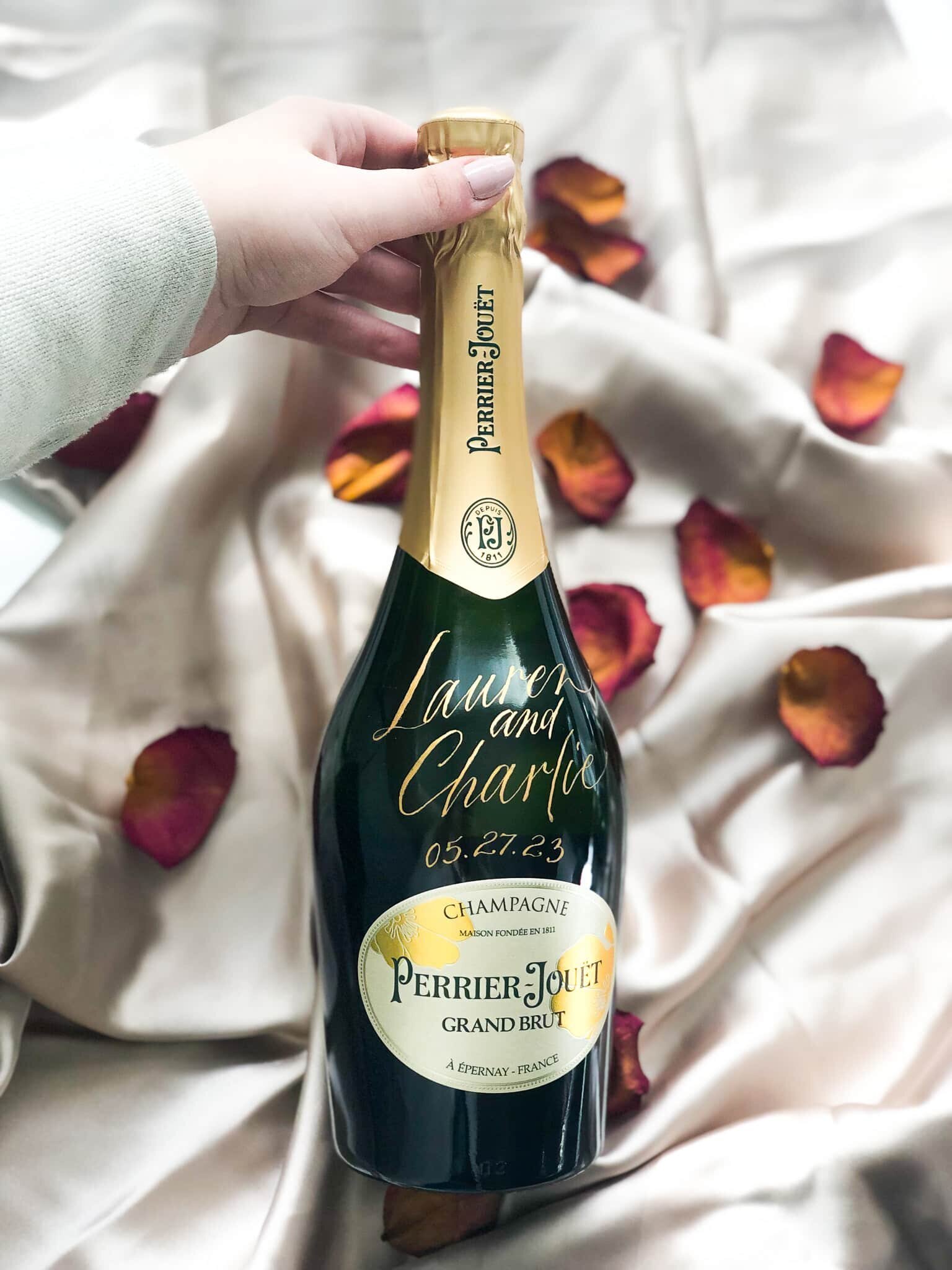 bottle of champagne on a taupe silk background surrounded by dried rose