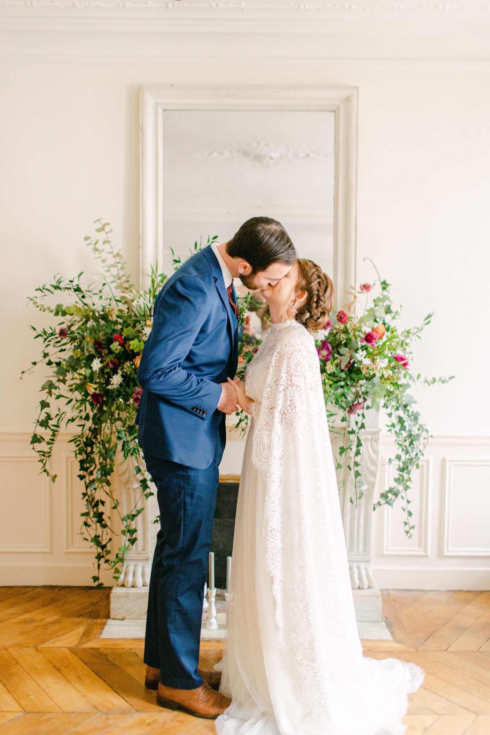bride and groom kiss in front of fireplace mantel in paris apartment
