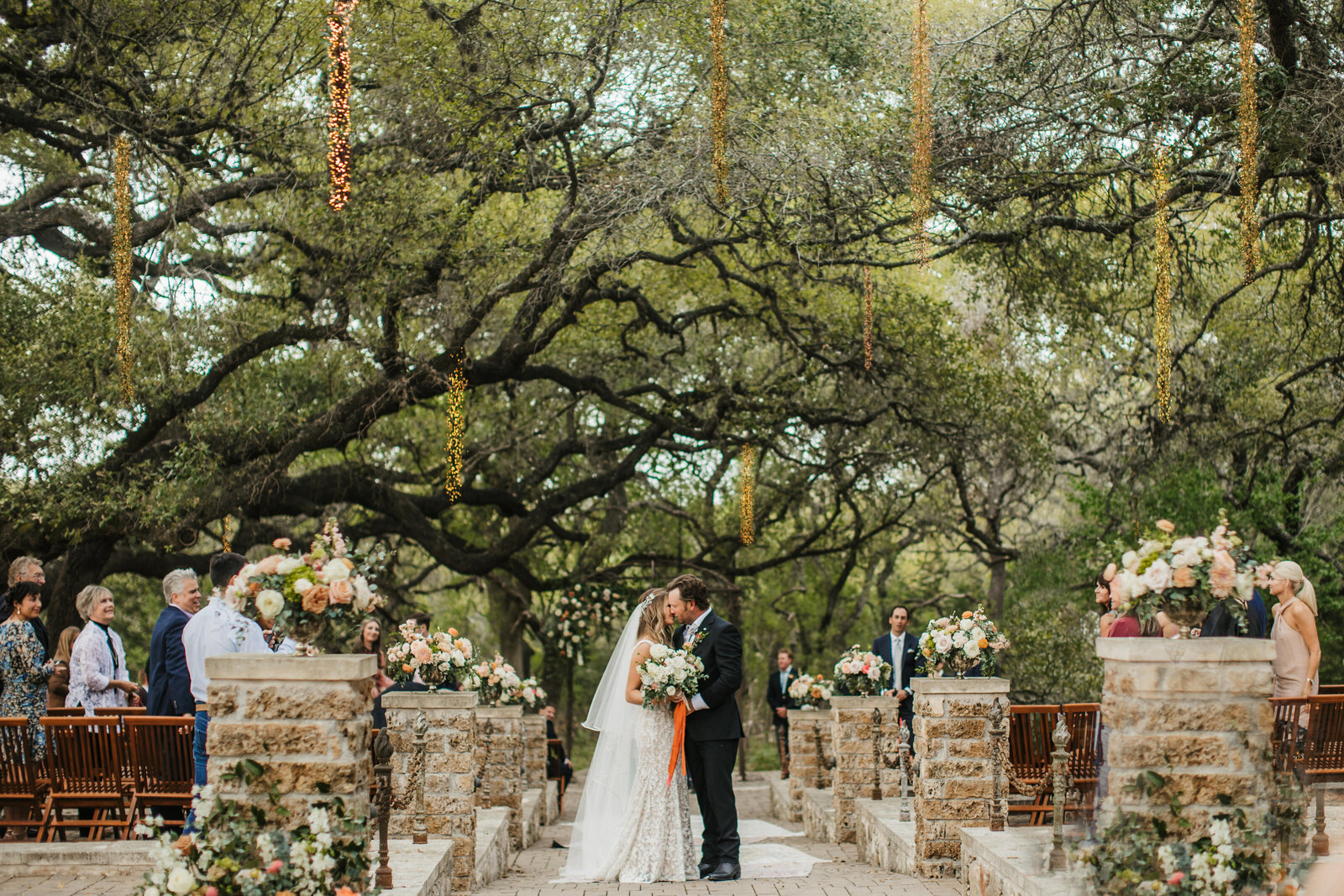 couple kiss on wedding aisle under Texas oak trees
