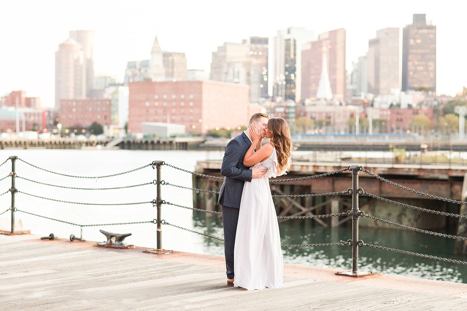 man and woman kissing with Boston skyline in background