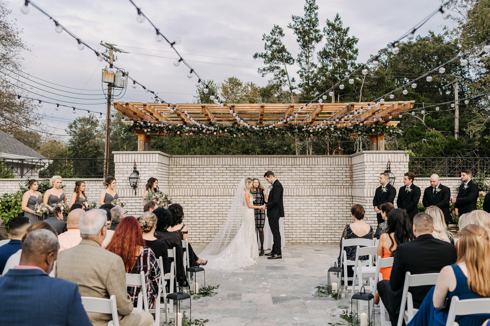 outdoor wedding ceremony with brick wall string lights
