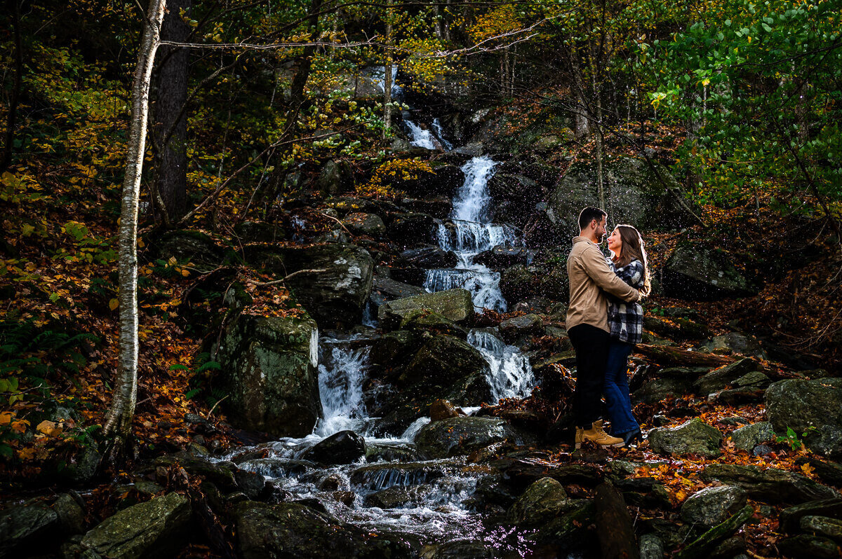 Couple by waterfall during peak foliage at smugglers notch