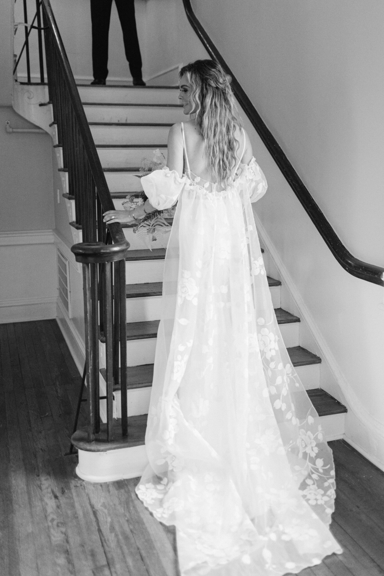 black and white photo of a bride walking up the stairs