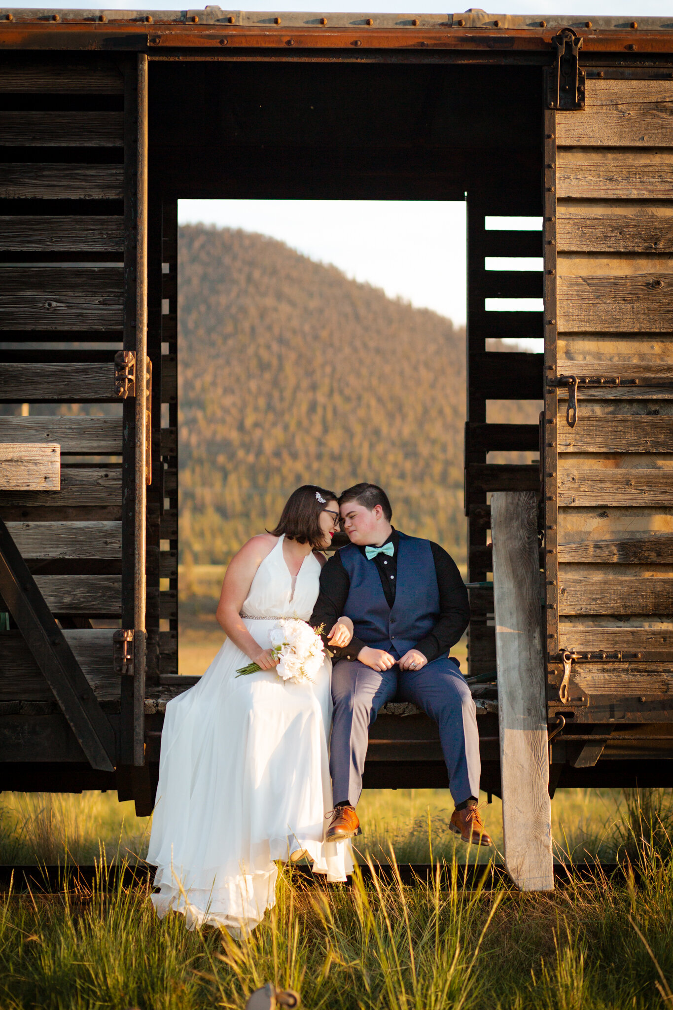 Couple sits together on an abandoned train car on their wedding day